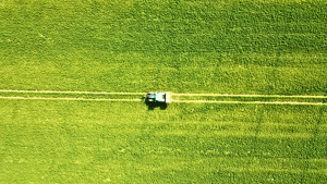 Tractor applying treatments to pasture during agricultural harvest, supporting safe crop storage outcomes.