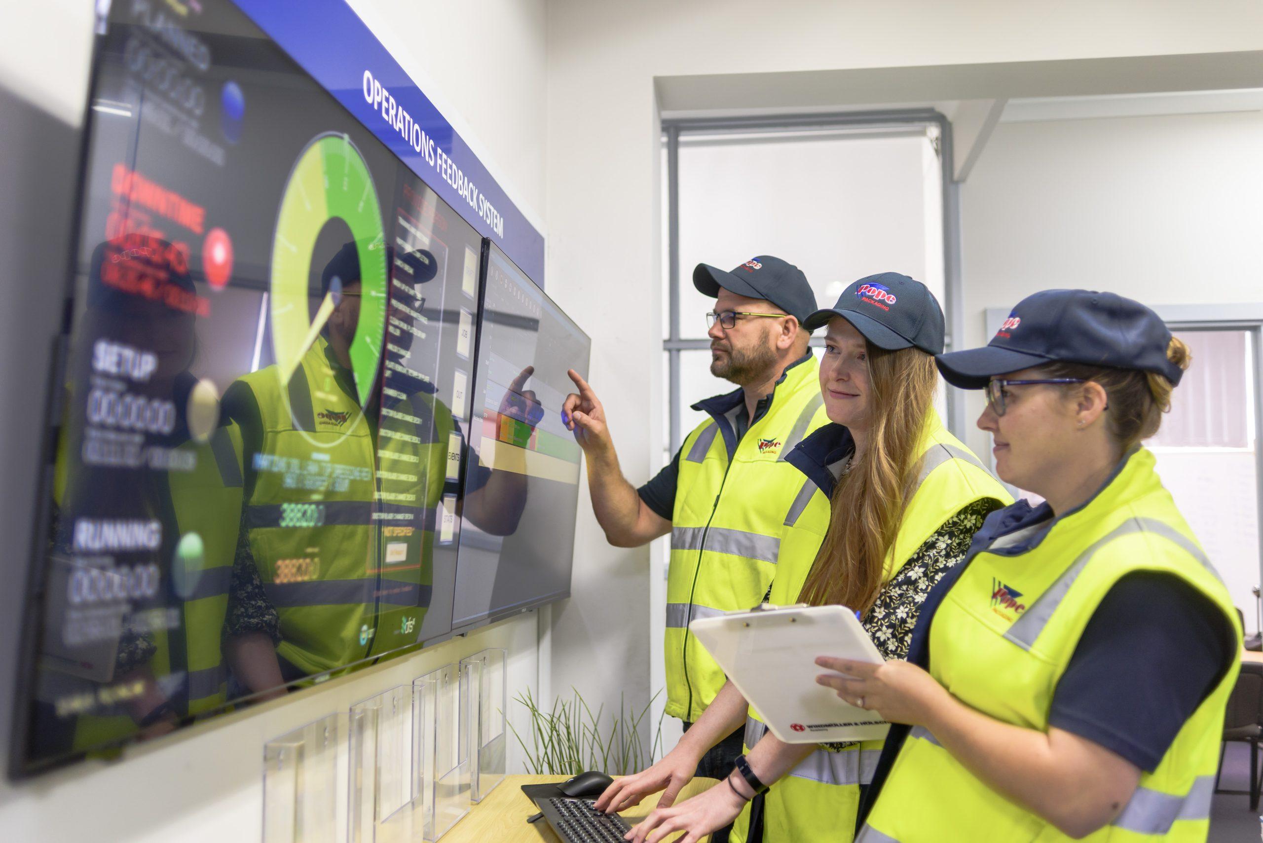 Team discussing print proofs for flexible packaging on digital press workstation.