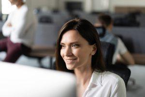 Young friendly office administrator USA sitting at her computer.